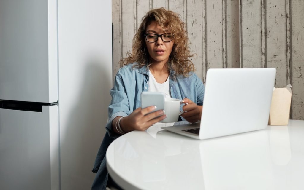 woman using smartphone and laptop