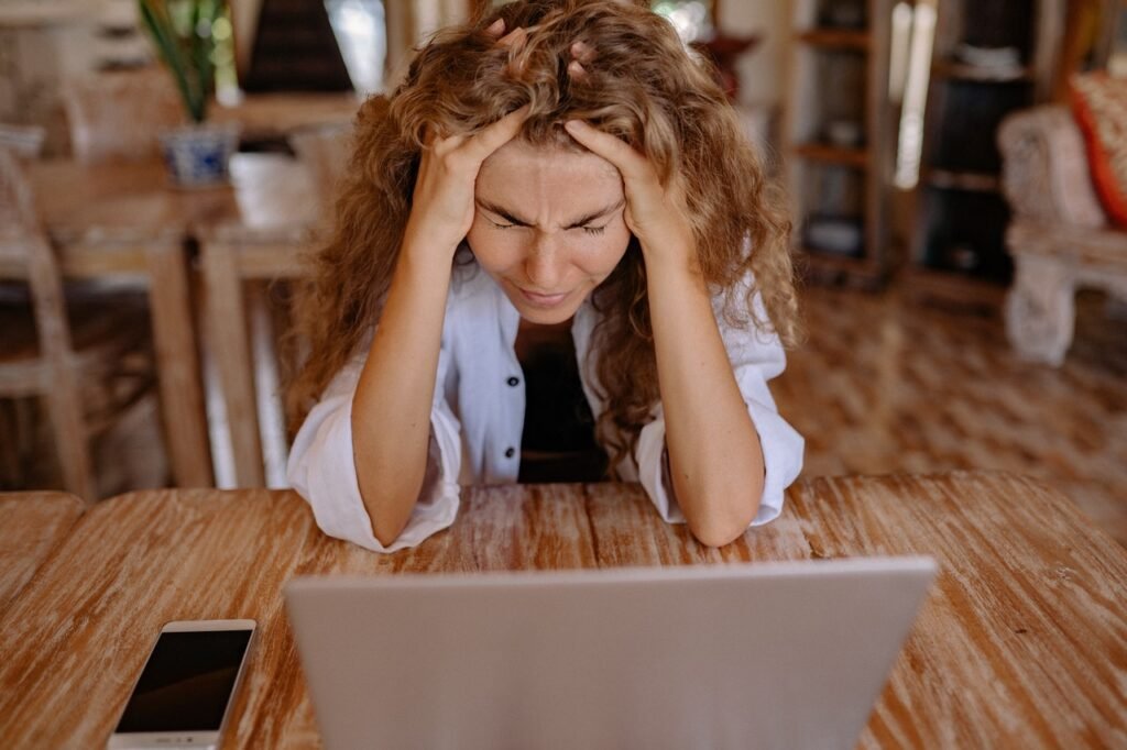 Woman holding her head in frustration in front of a computer.