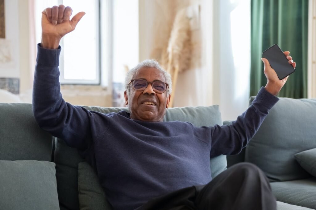 Man holding smartphone with hands raised in triumph.